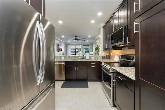 a kitchen with stainless steel appliances granite countertop a refrigerator a stove and a sink