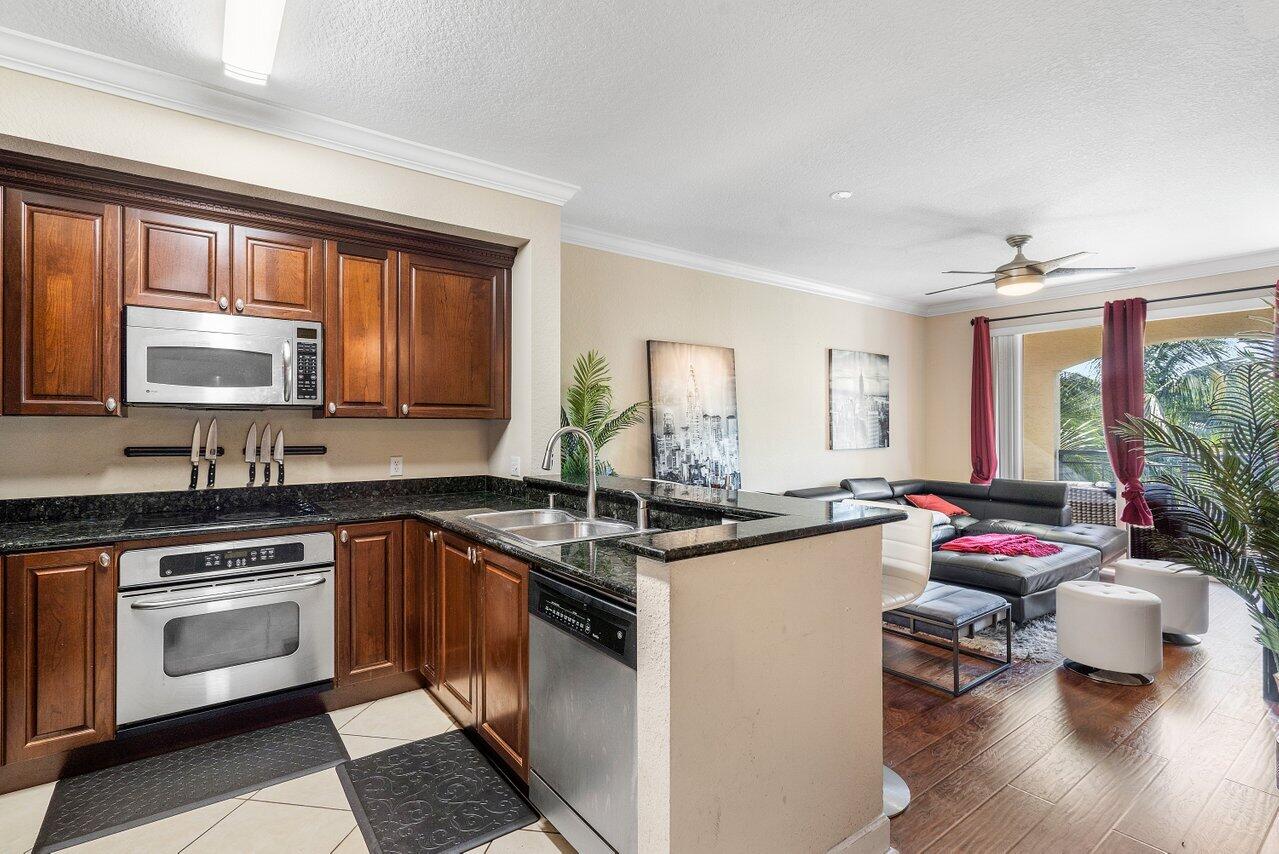 1 Renaissance Way, Unit 416 Boynton Beach, FL 33426 - Photo 4 of 31 a kitchen with kitchen island granite countertop a sink cabinets and stainless steel appliances