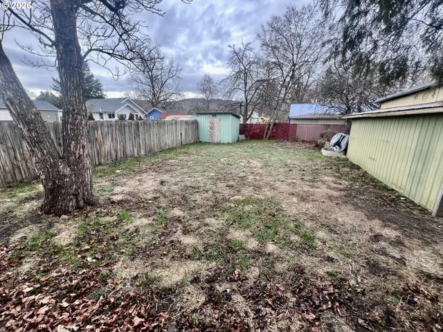 a backyard of a house with a tree and wooden fence