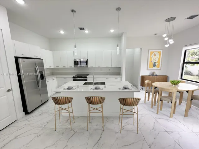 a kitchen with stainless steel appliances kitchen island granite countertop a refrigerator a stove a sink a dining table and chairs