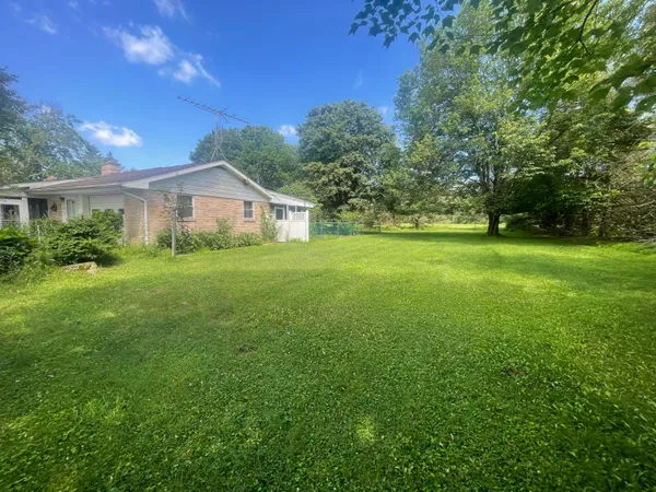 a view of a house with a big yard and large trees