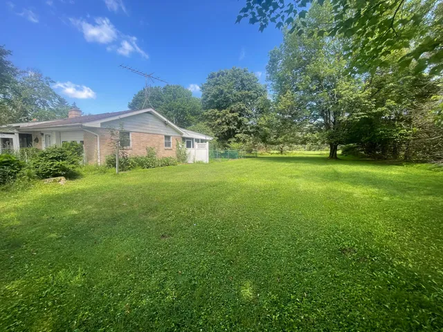a view of a house with a big yard and large trees