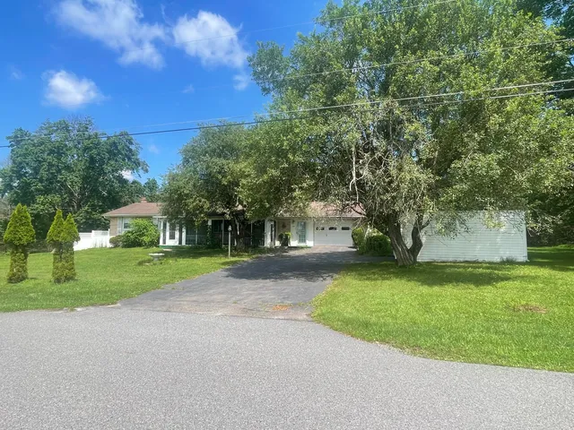 a view of a house with a big yard and large trees