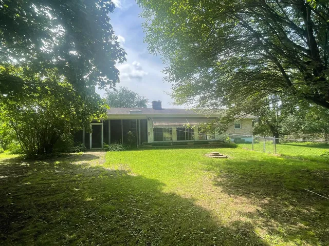 a view of a house with a big yard and large trees