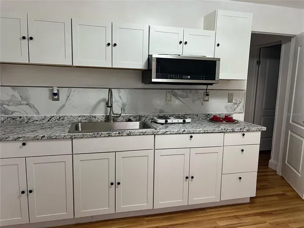 a kitchen with granite countertop white cabinets and stainless steel appliances