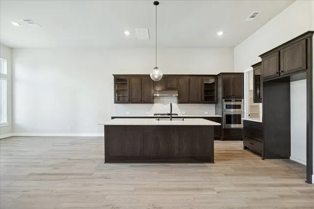a view of kitchen with stainless steel appliances granite countertop cabinets and wooden floor