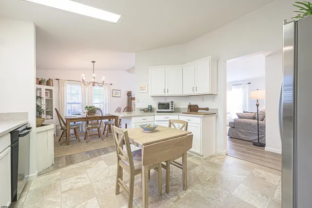 a kitchen with stainless steel appliances kitchen island granite countertop a table chairs sink and cabinets