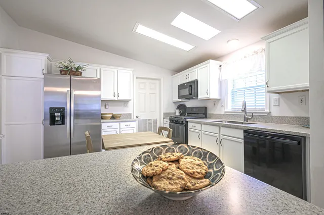 a kitchen with granite countertop a stove refrigerator and microwave