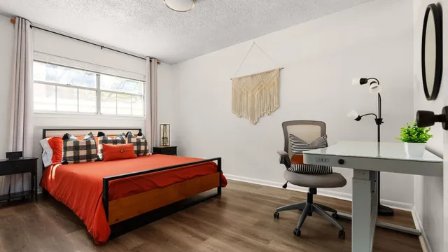 a bedroom with a bed a chair and a potted plant on the dresser