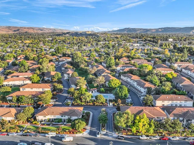 an aerial view of residential houses with outdoor space and trees