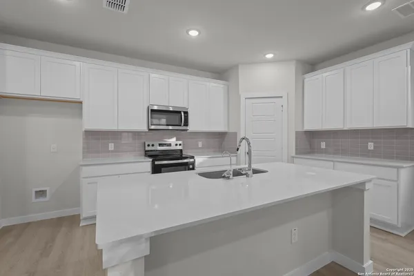 a kitchen with appliances a sink and cabinets