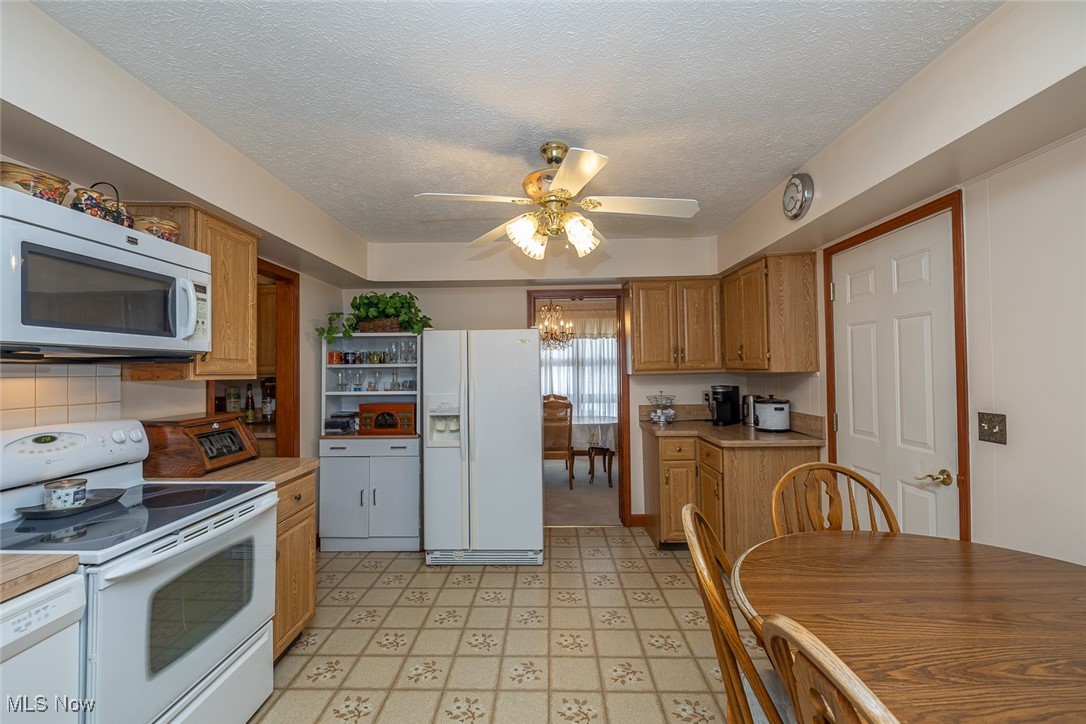 750 Sagamore Road Northfield, OH 44067 - Photo 3 of 37 Kitchen featuring tasteful backsplash, ceiling fan with notable chandelier, white appliances, and a textured ceiling