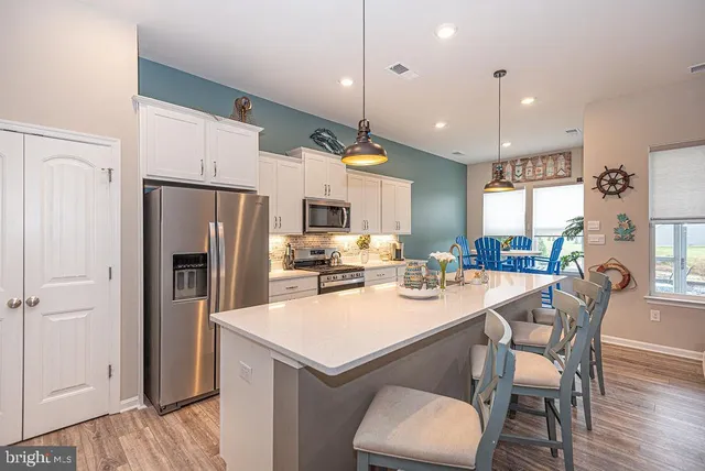 a kitchen with a refrigerator a dining table and chairs
