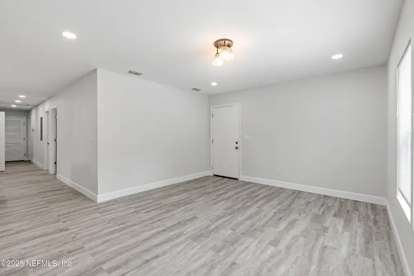 an empty room with wooden floor ceiling fan and windows