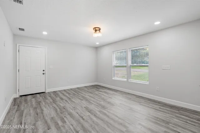 an empty room with wooden floor and windows