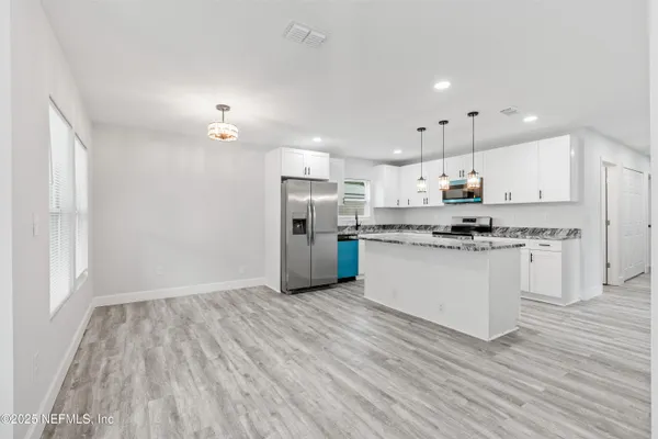 a kitchen with stainless steel appliances granite countertop a sink a stove a refrigerator and island with wooden floor