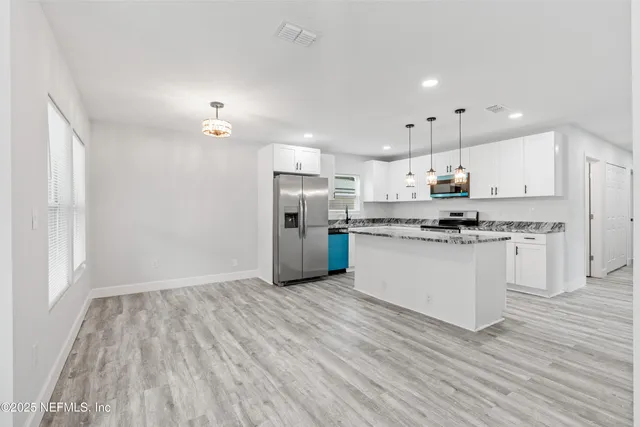 a kitchen with stainless steel appliances granite countertop a sink a stove a refrigerator and island with wooden floor