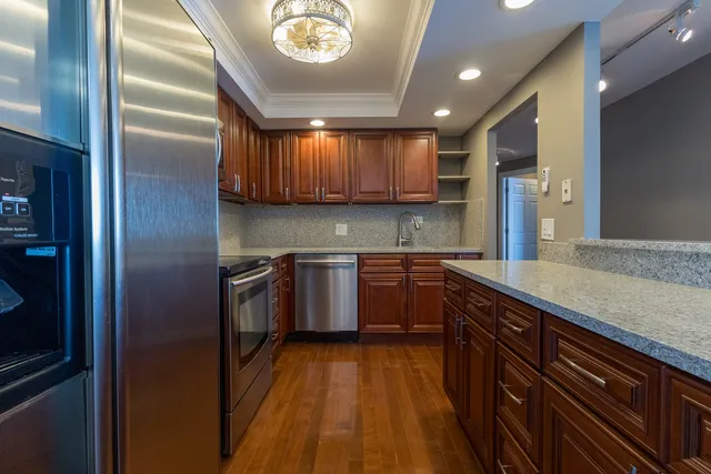 a kitchen with stainless steel appliances granite countertop a sink a stove and a refrigerator