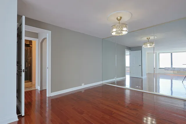 a view of an empty room with a window and wooden floor