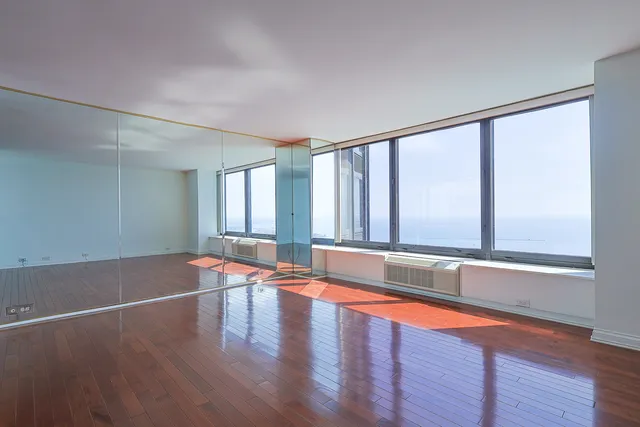 an empty room with large windows and wooden floor