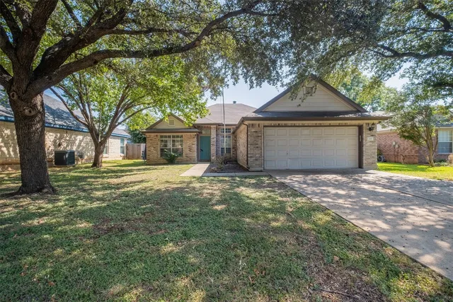 a front view of a house with a yard and large tree