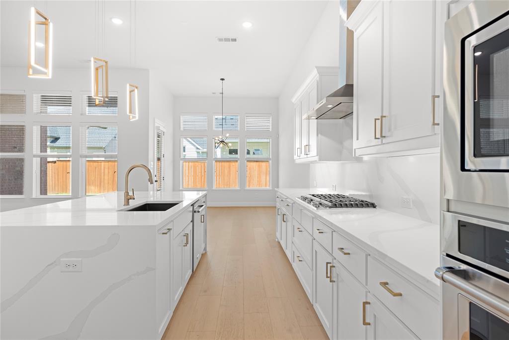 4405 Rosedale Street Prosper, TX 75078 - Photo 6 of 40 a kitchen with kitchen island granite countertop a sink appliances cabinets and a counter top space