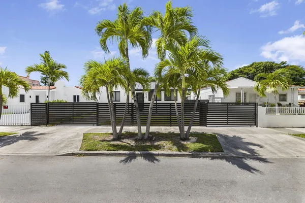 a front view of a house with a yard and palm tree