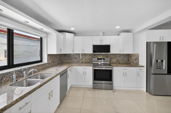 a kitchen with stainless steel appliances granite countertop a sink stove and refrigerator