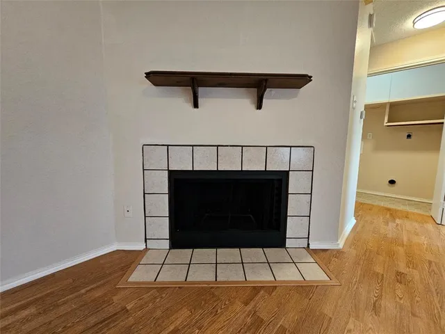 a view of an empty room with wooden floor and a fireplace