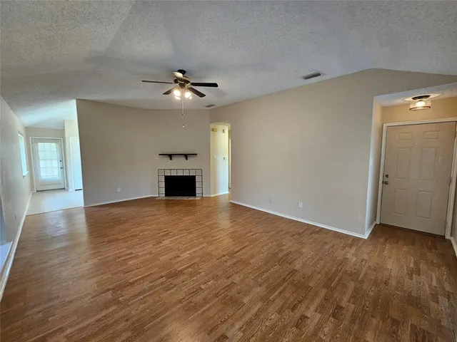 an empty room with wooden floor ceiling fan and windows