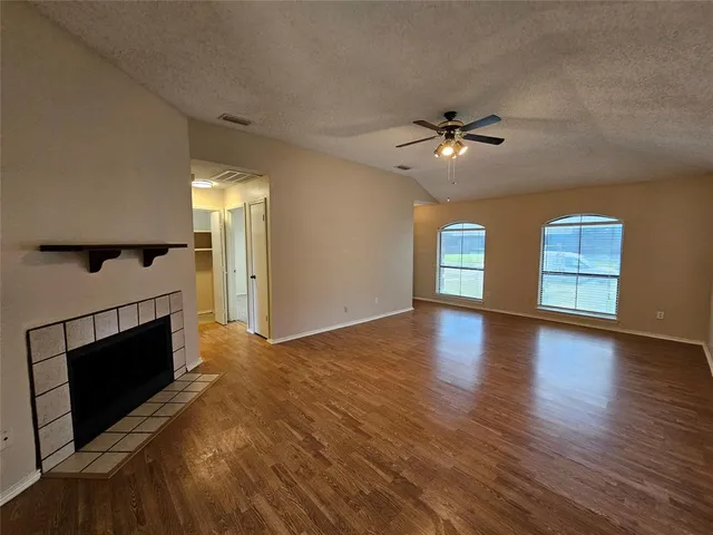 a view of empty room with wooden floor and fireplace