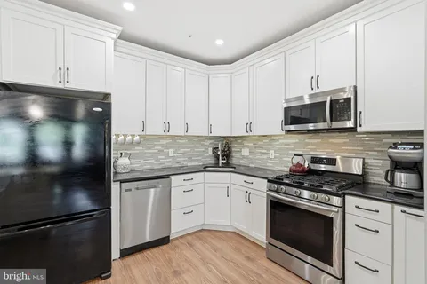 a kitchen with granite countertop white cabinets and stainless steel appliances