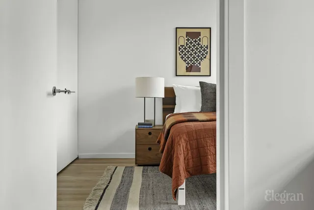 a bedroom with a bed a mirror and a large window