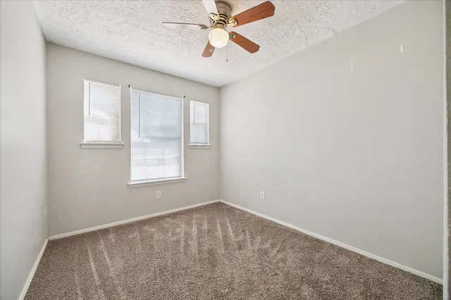 an empty room with a window and a fan