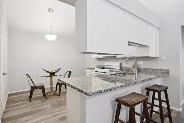 a kitchen with granite countertop a table chairs stove and microwave