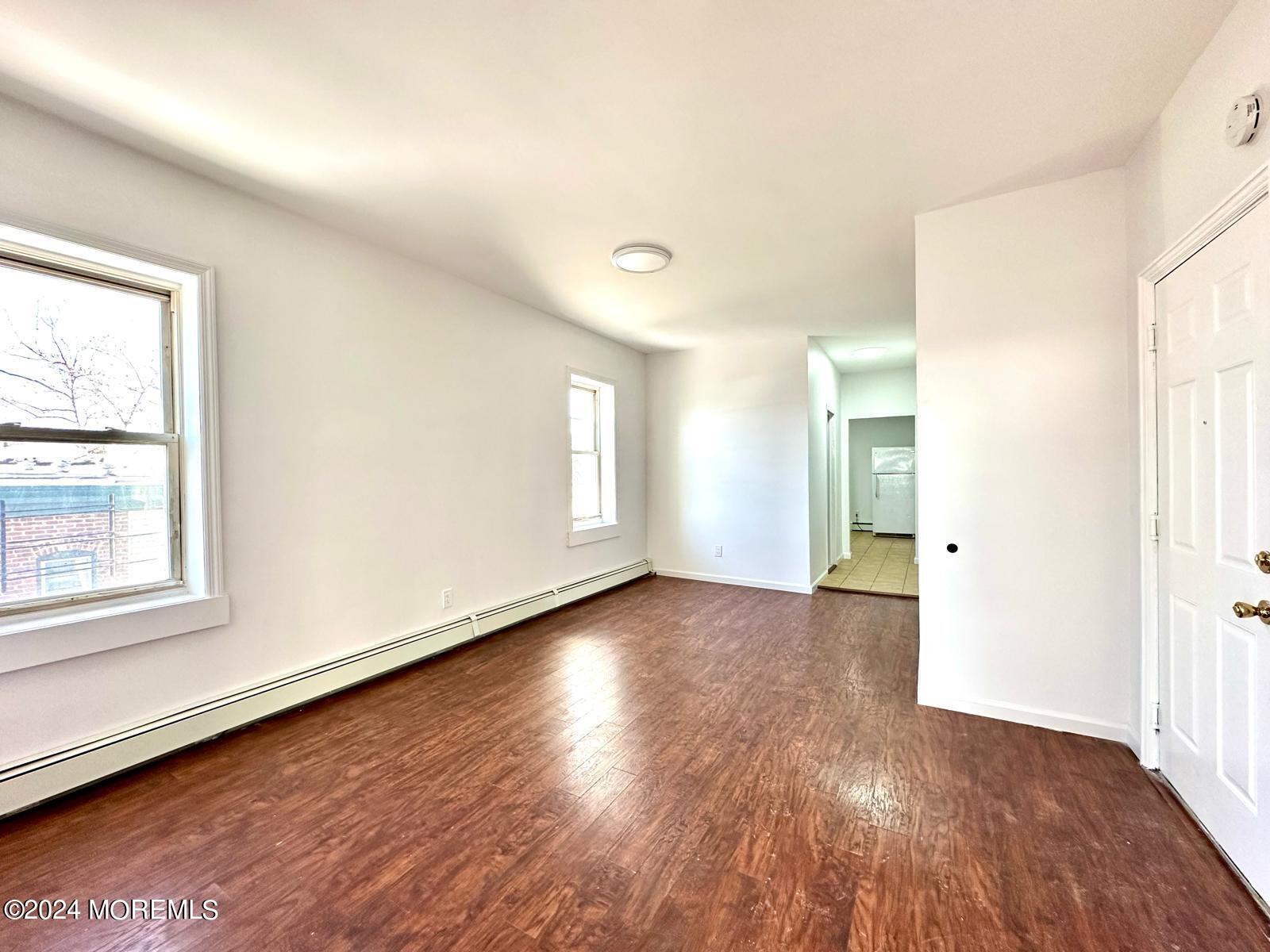 462 Compton Avenue, Unit THIRD Perth Amboy, NJ 08861 - Photo 4 of 14 an empty room with wooden floor and windows