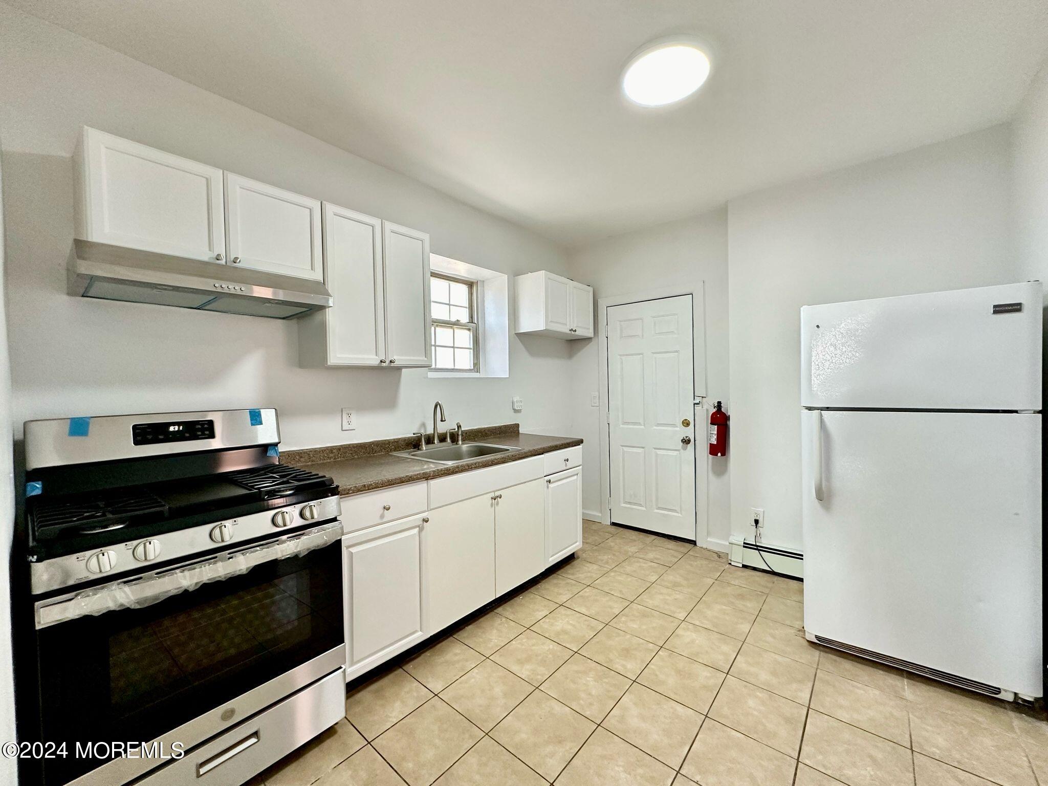 462 Compton Avenue, Unit THIRD Perth Amboy, NJ 08861 - Photo 9 of 14 a kitchen with granite countertop white cabinets and white appliances