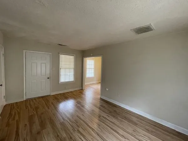 a view of an empty room with wooden floor and window