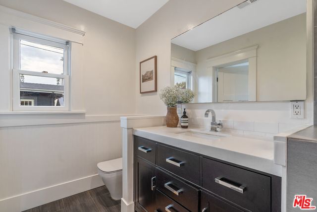 a bathroom with a granite countertop sink a toilet and a mirror