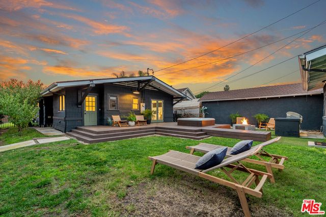 a view of backyard of house with wooden deck and outdoor seating