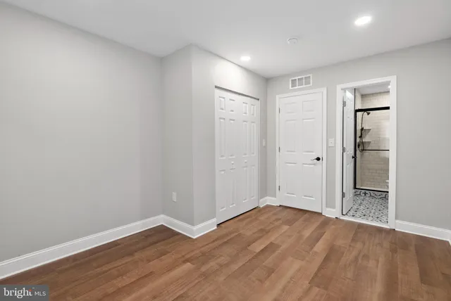 a view of an empty room with wooden floor and closet
