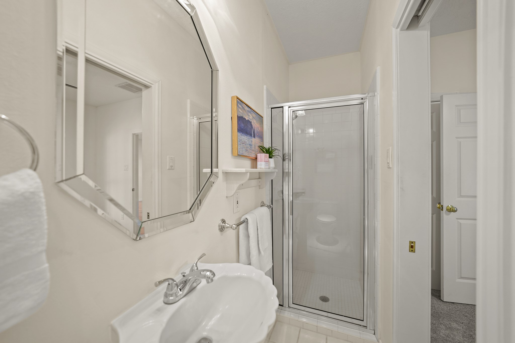 12690 Longmire Way Conroe, TX 77304 - Photo 38 of 50 The ensuite bath has a pedestal sink highlighted by a beveled mirror with wall mounted lighting above, a glass enclosed shower & tile flooring.