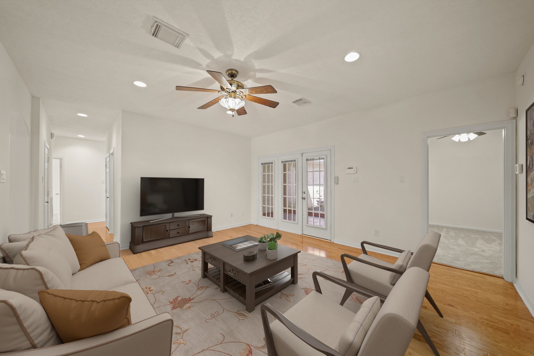 12690 Longmire Way Conroe, TX 77304 - Photo 9 of 50 Features include recessed lighting, a ceiling fan with light fixture & hardwood floors. The door on the right leads to a private secondary bedroom complete with an ensuite bath. This photo has been virtually staged.