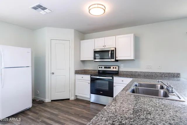a kitchen with granite countertop white cabinets white stainless steel appliances a sink and a window