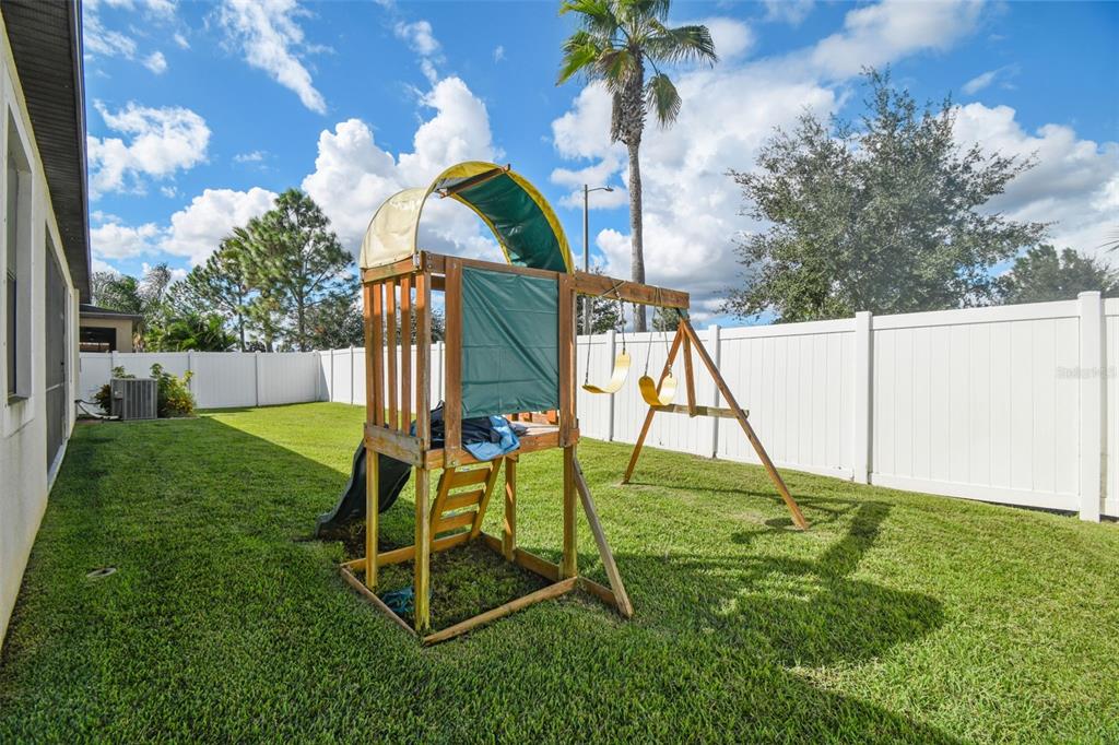 13807 Felix Will Road Riverview, FL 33579 - Photo 74 of 91 a view of a backyard with a slide trees and wooden fence