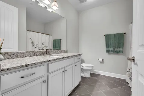 a bathroom with a granite countertop sink a toilet and a mirror