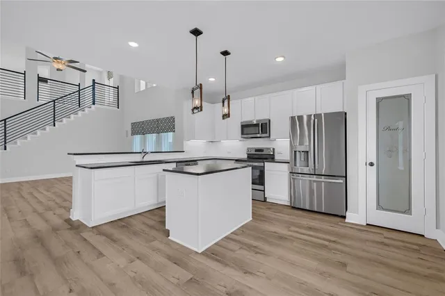 a kitchen with kitchen island white cabinets and stainless steel appliances