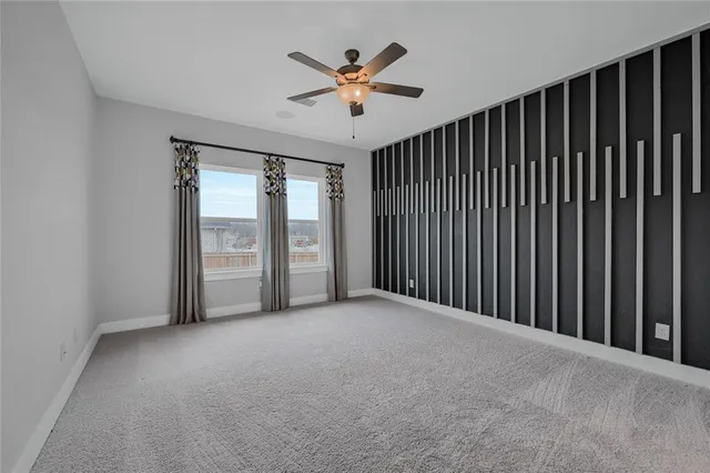 an empty room with ceiling fan and windows