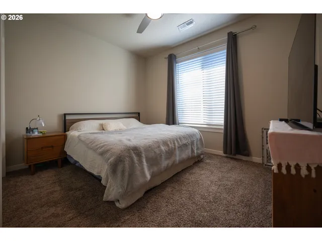 a bedroom with a bed and a flat tv screen on dresser