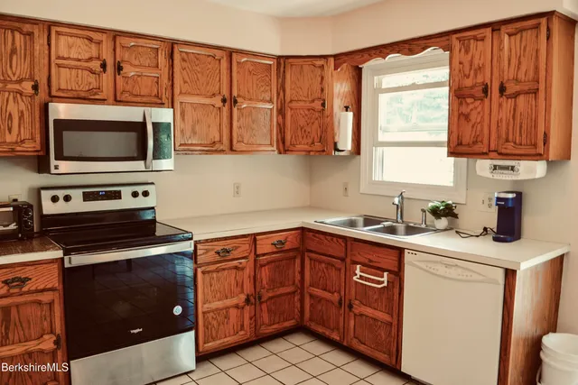 a kitchen with stainless steel appliances granite countertop a sink dishwasher stove and microwave with wooden cabinets
